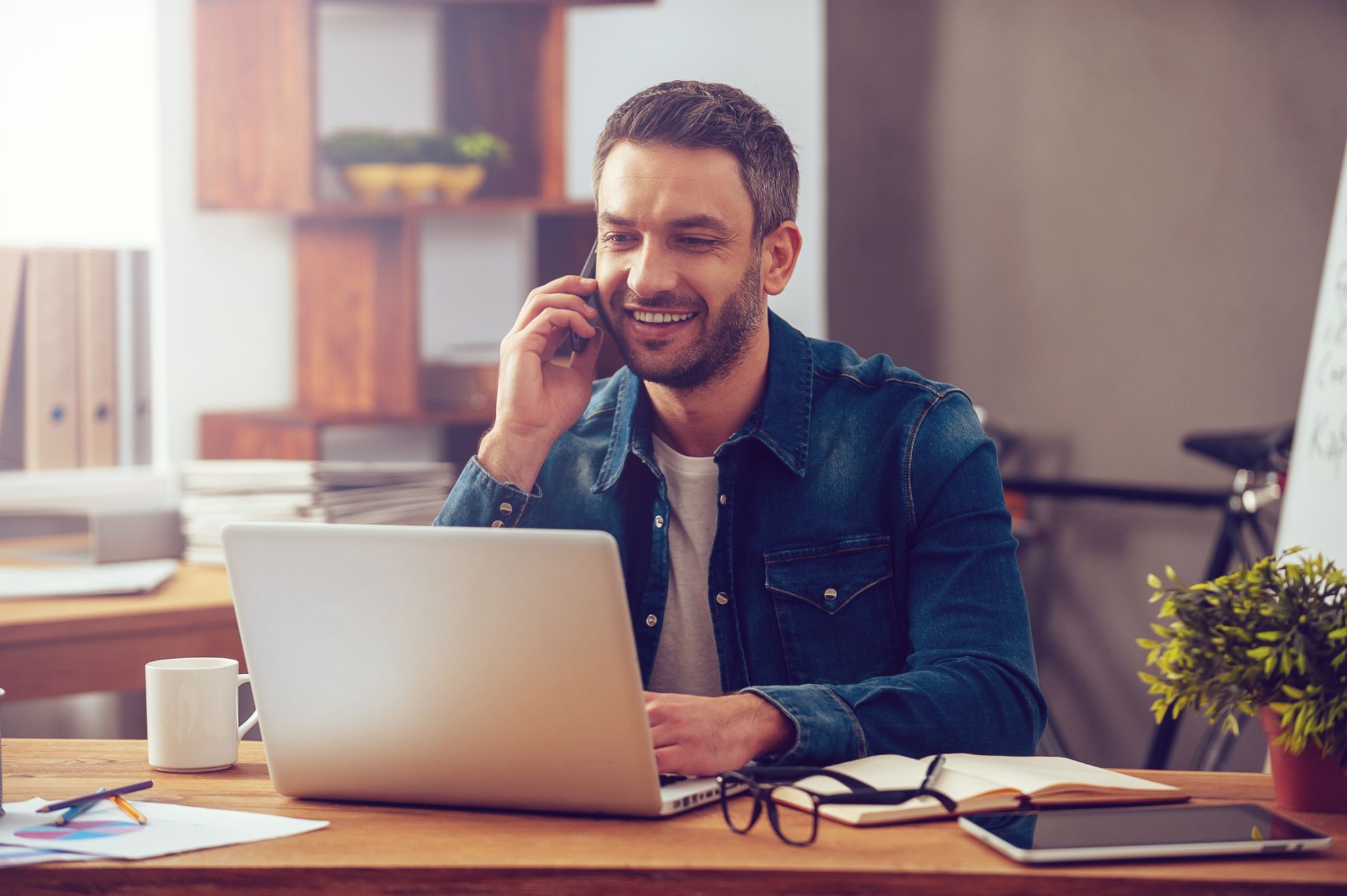 Business man working on computer while talking on the phone
