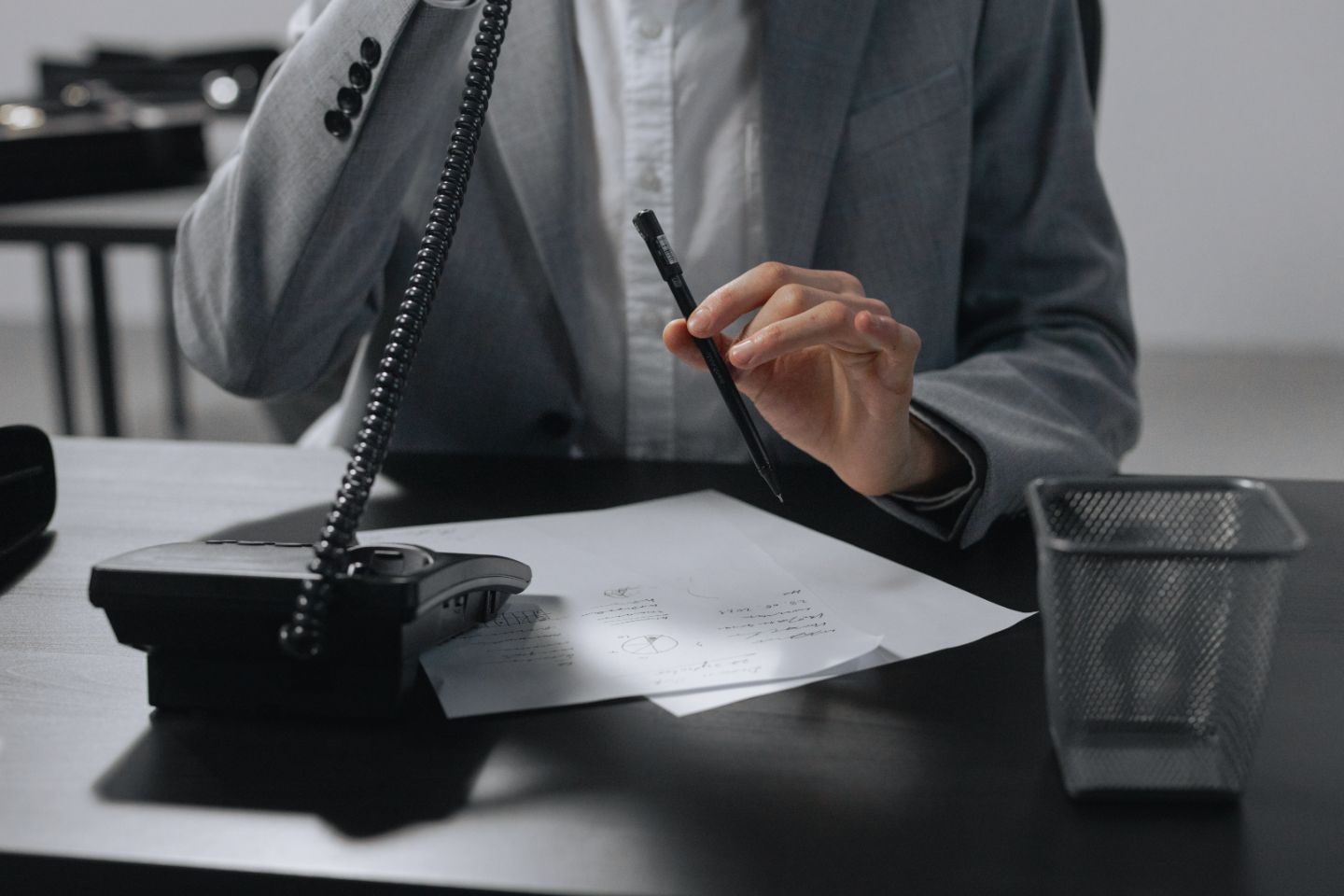 person talking on phone and holding a pen