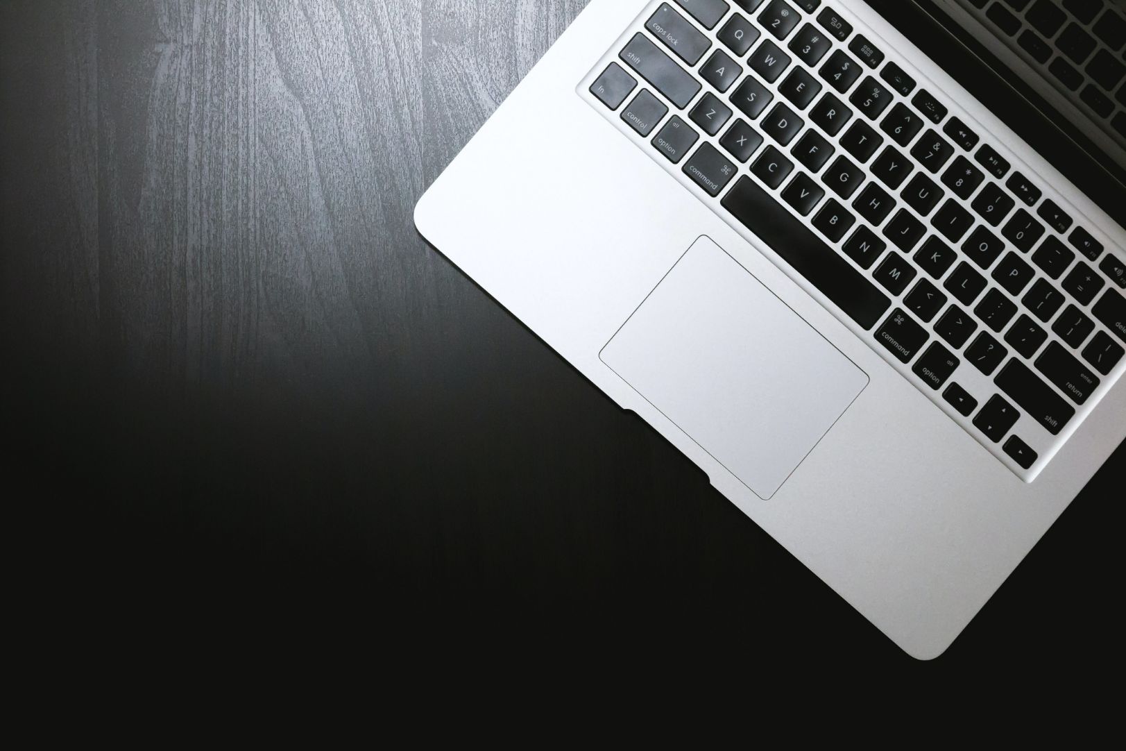 Open laptop keyboard on black wooden surface