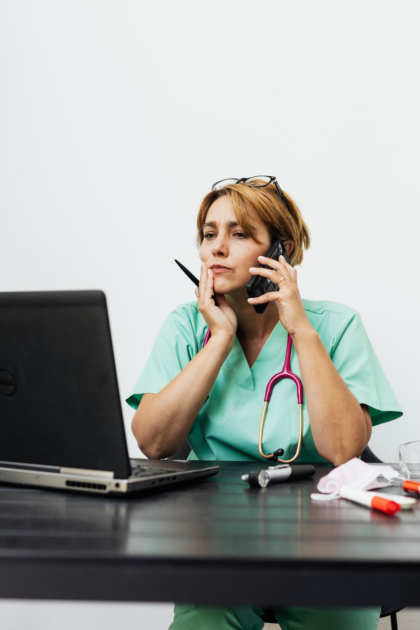 Nurse talking on the phone while working on a laptop