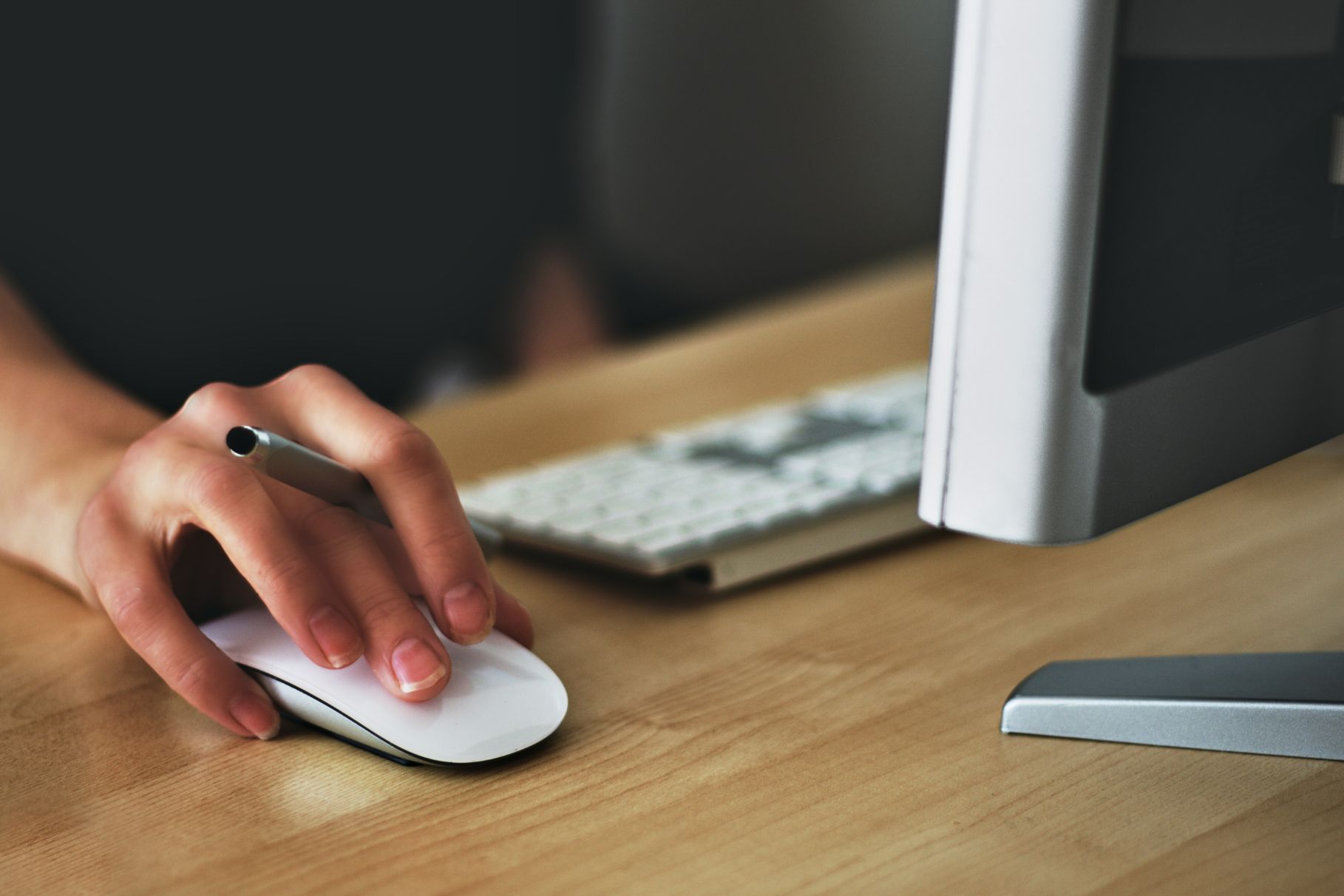 Persons hand on computer mouse working on a computer at a desk