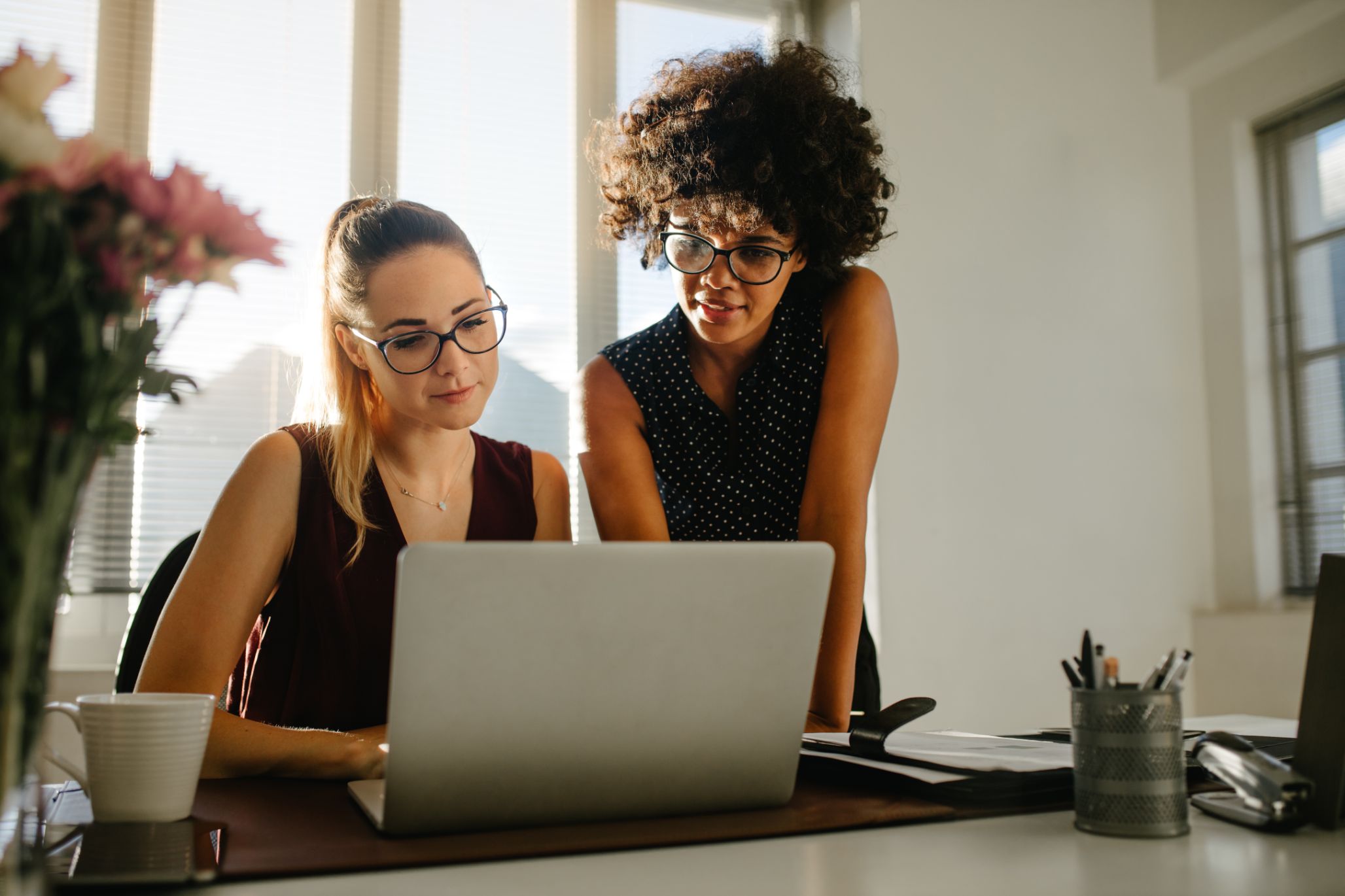 Two business woman working on laptop together