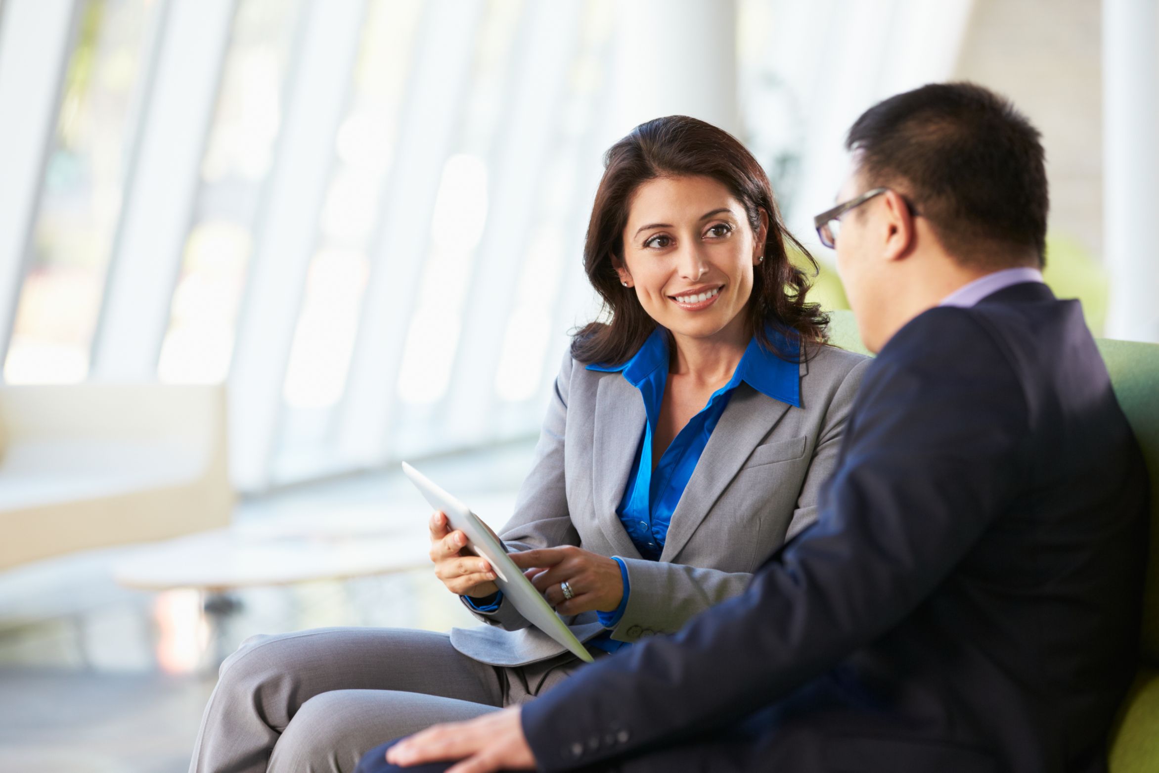 Two business people talking and working on tablet