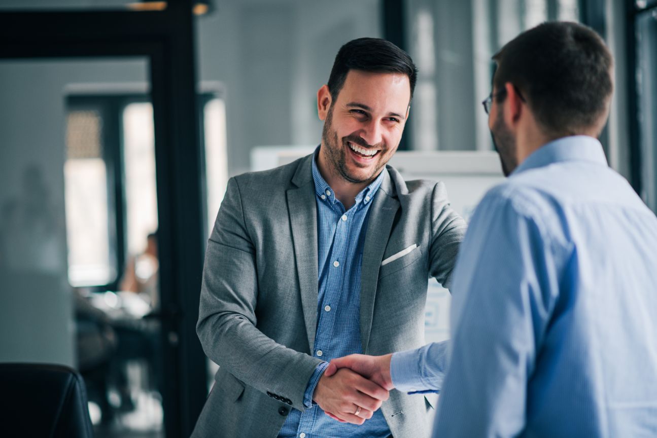 Two business men shaking hands and smiling