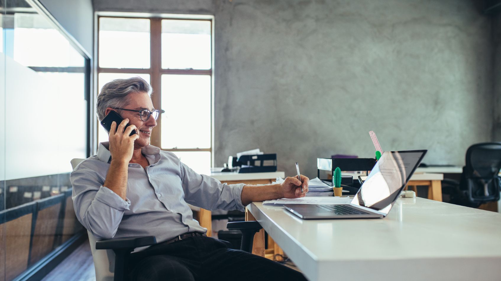 Business man talking on the phone while working on a laptop