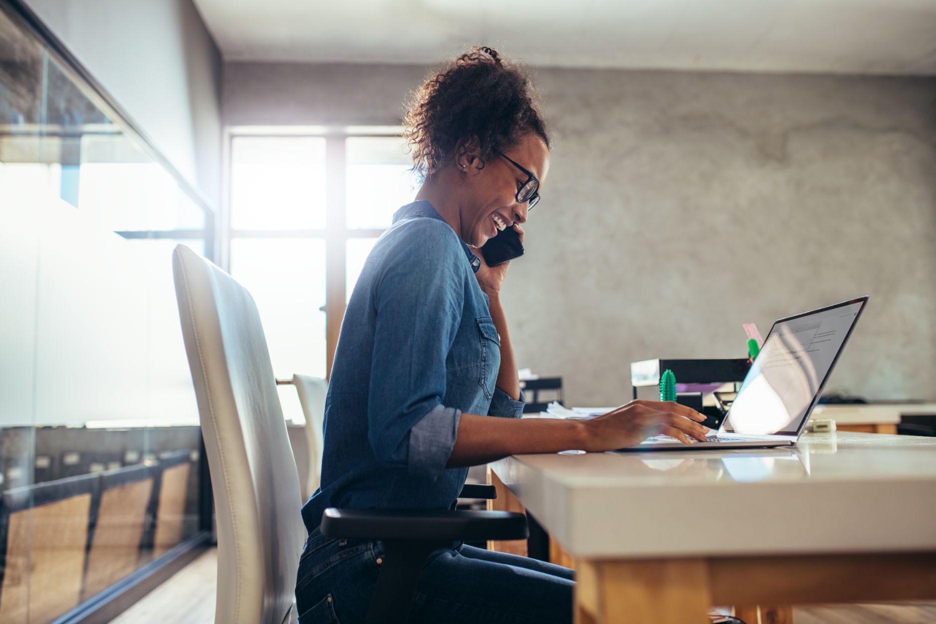 Business woman talking on phone while working on computer