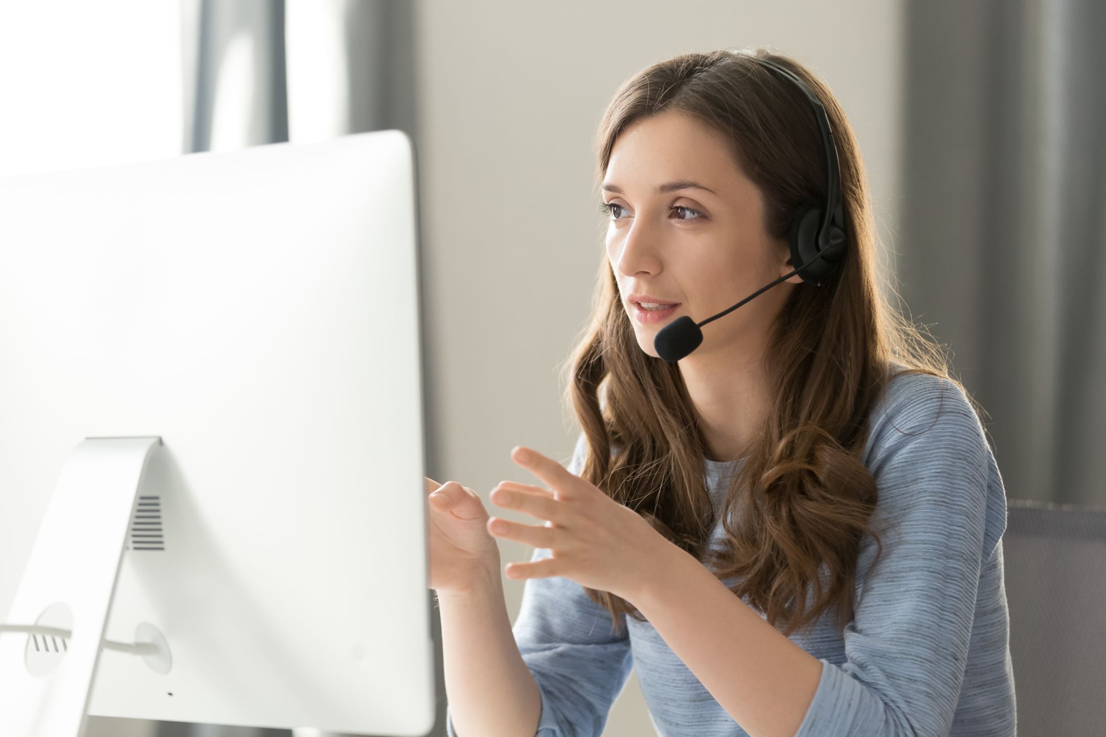 Business woman talking on headset while looking at computer