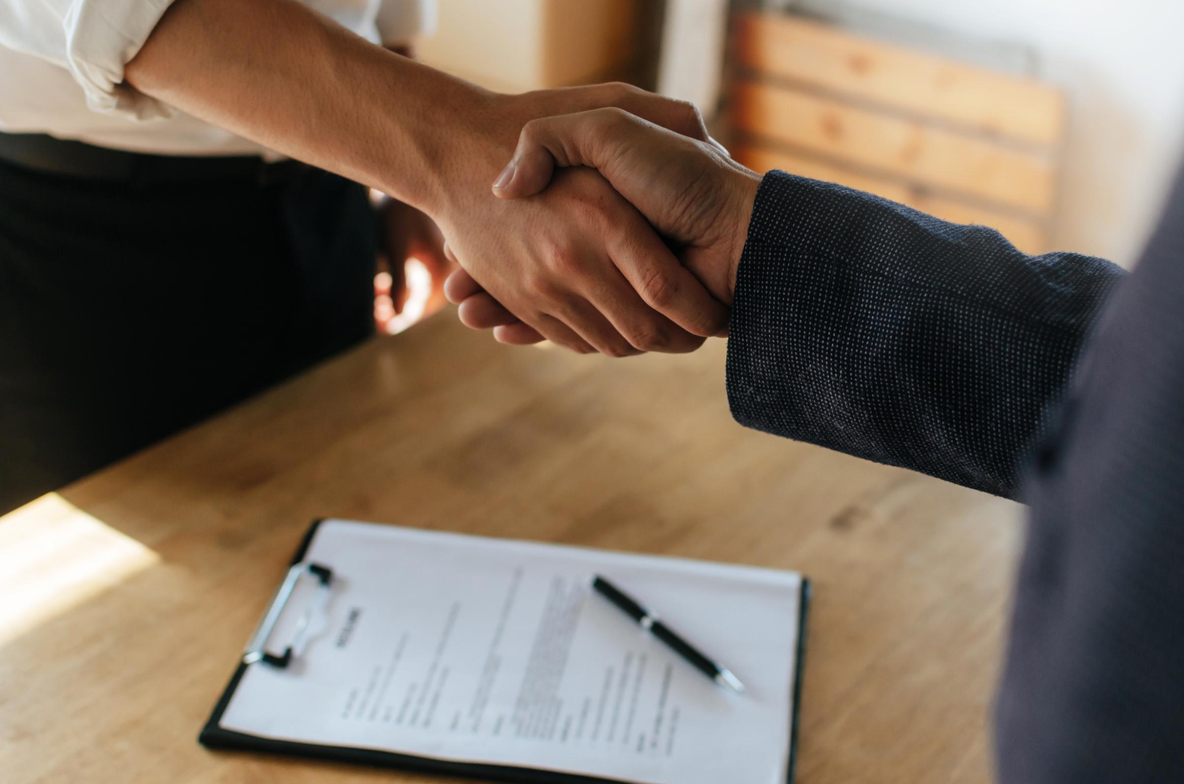 Business people shaking hands over signed contract