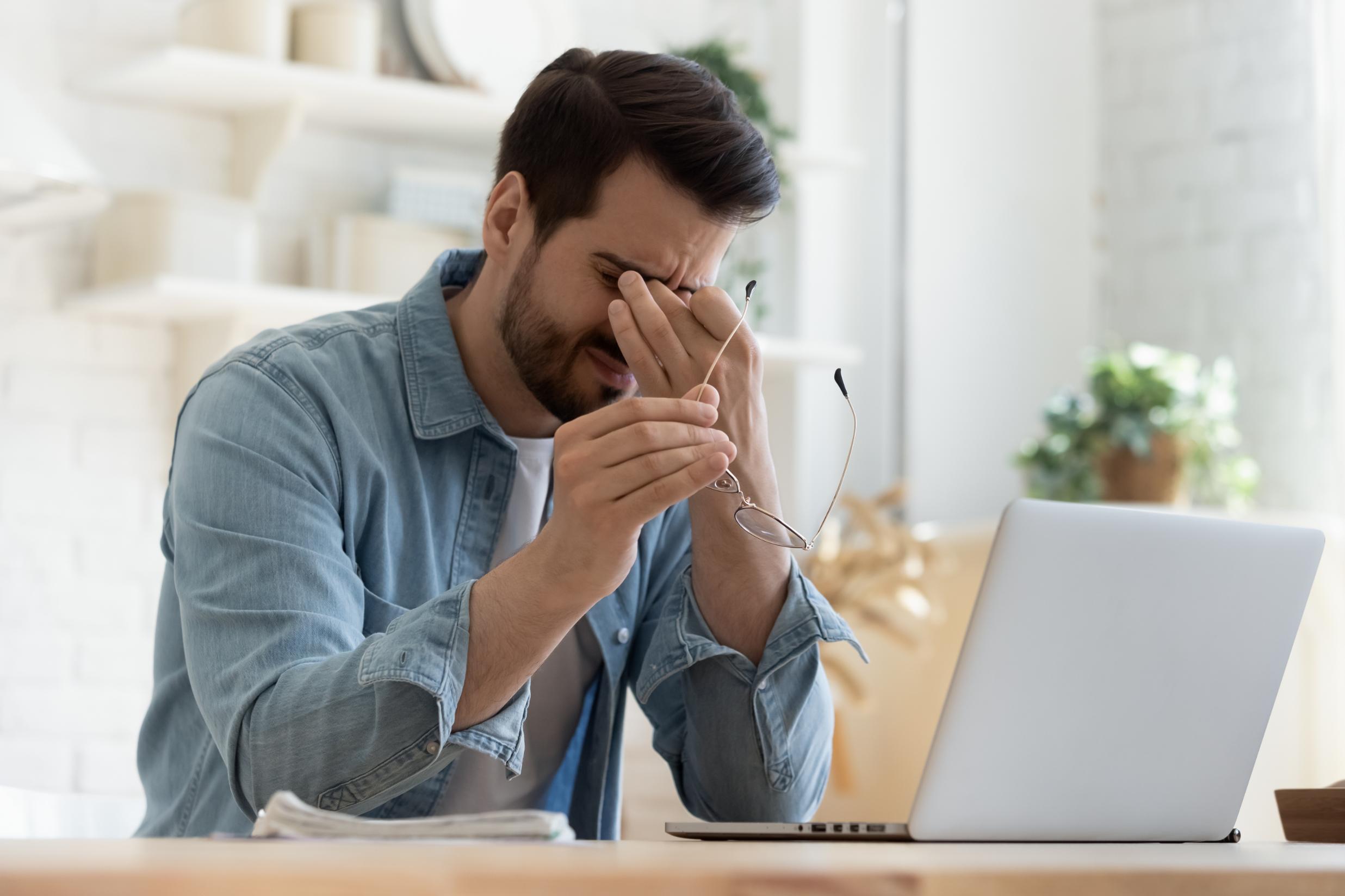 Business man working on computer rubbing eyes