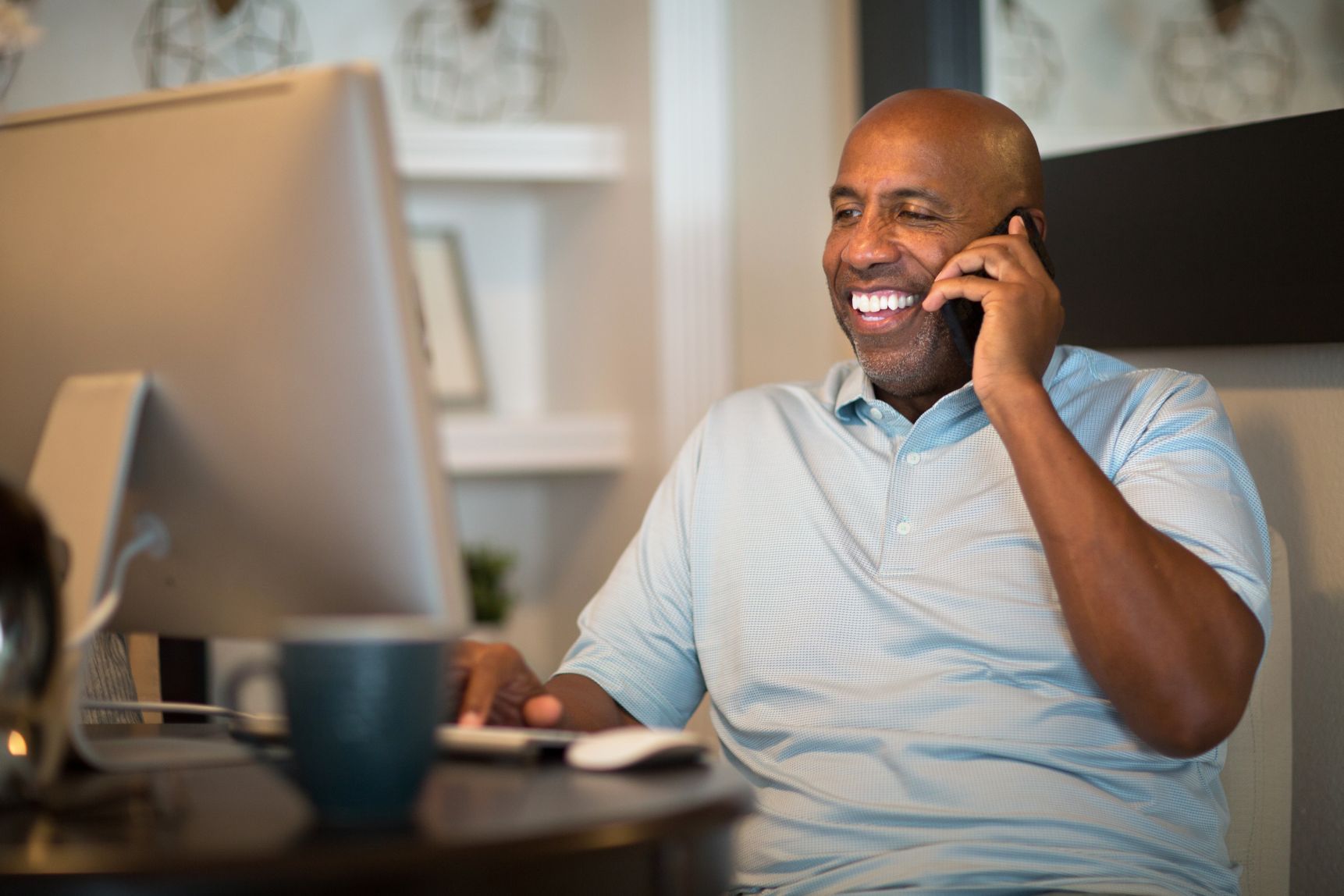 Man talking on phone and looking at computer screen 