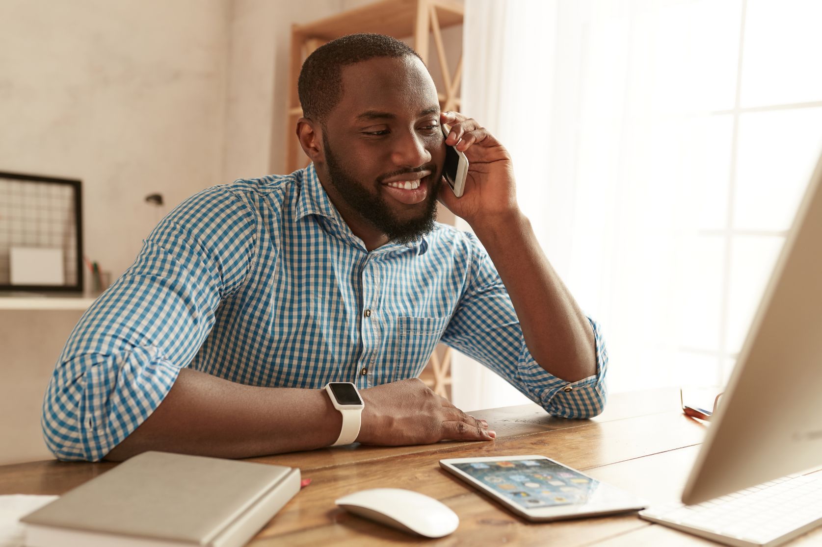 Business man talking on phone while working on a laptop at a desk 