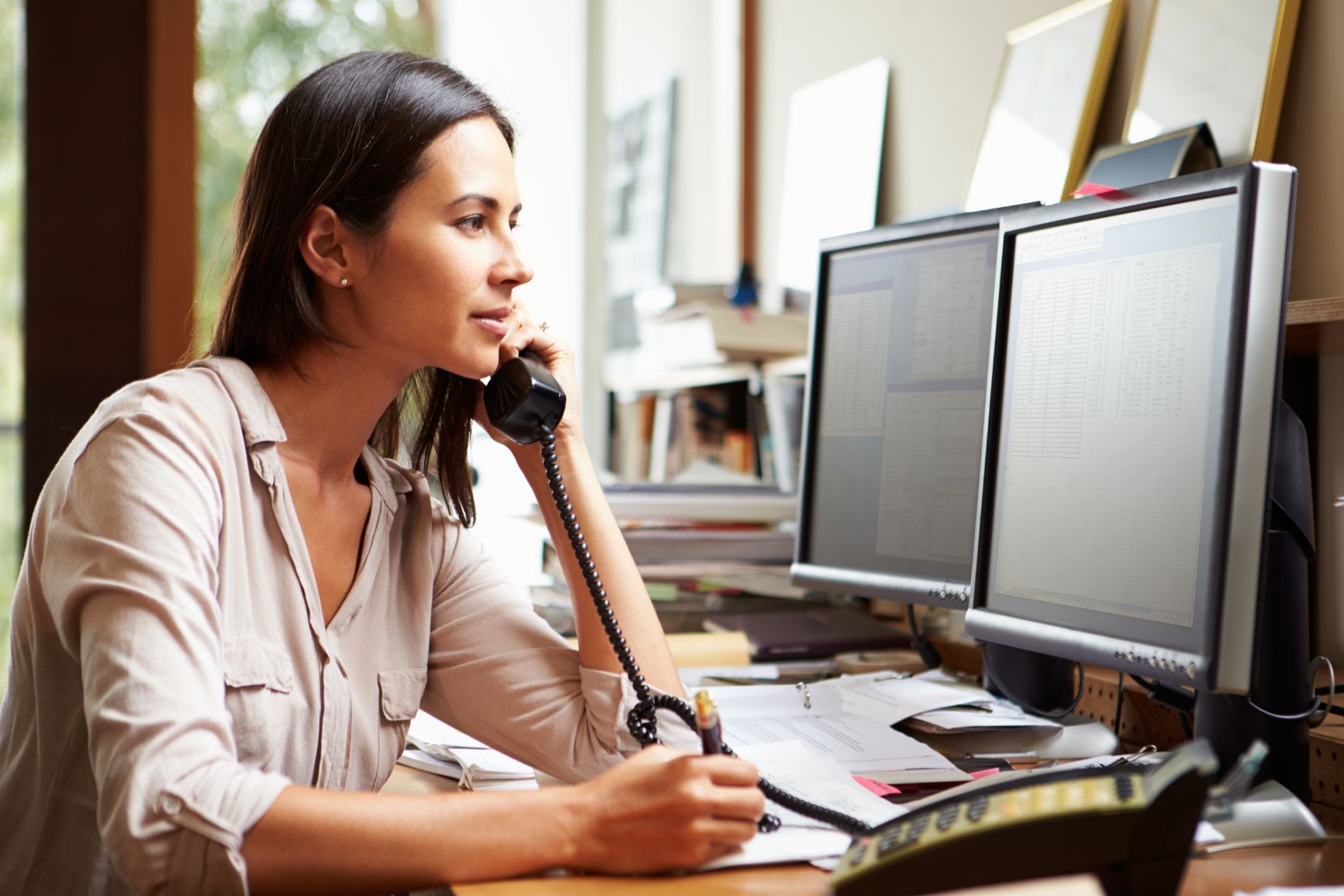 Business woman on the phone while working on computer 