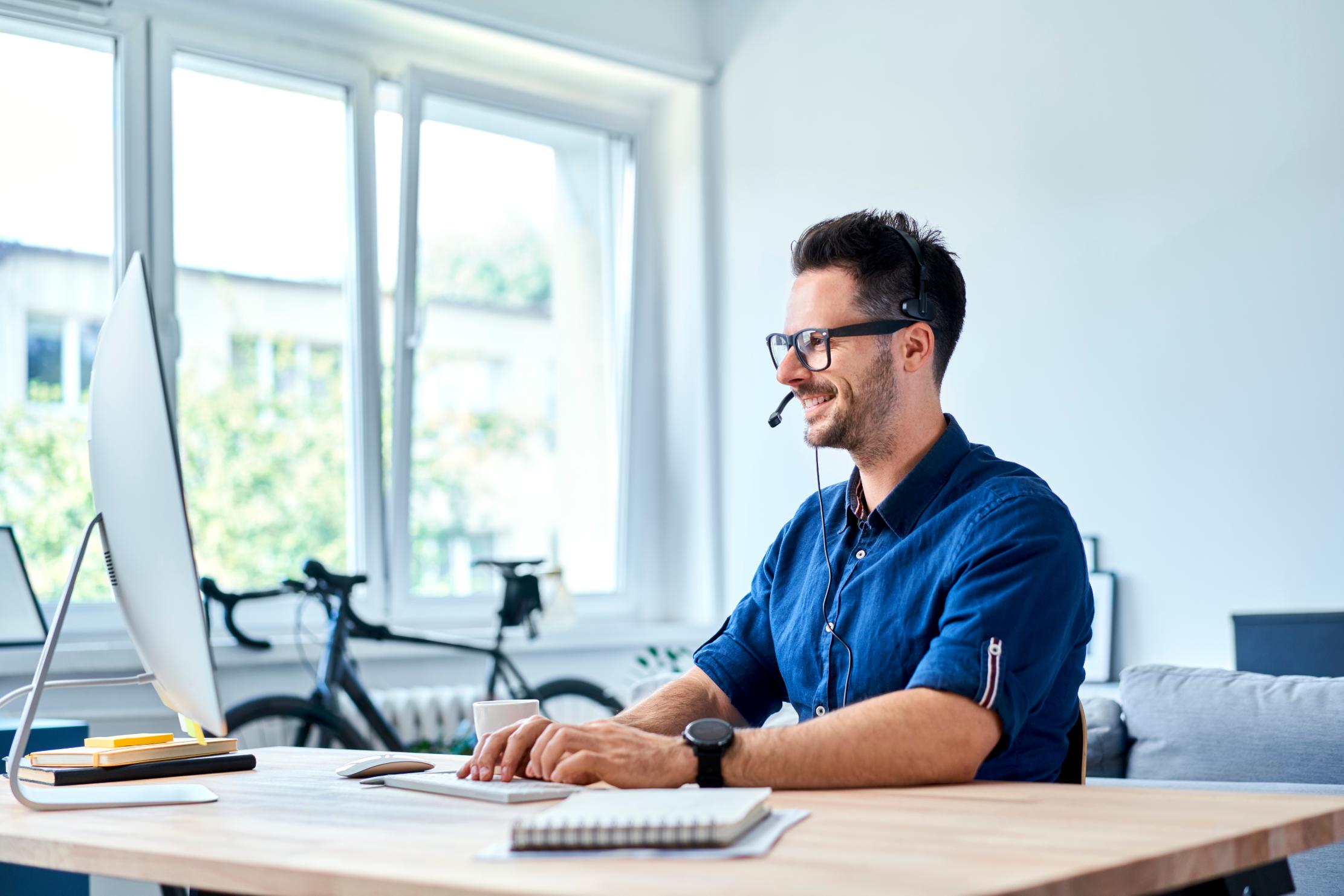 Business man working on laptop while talking into headset