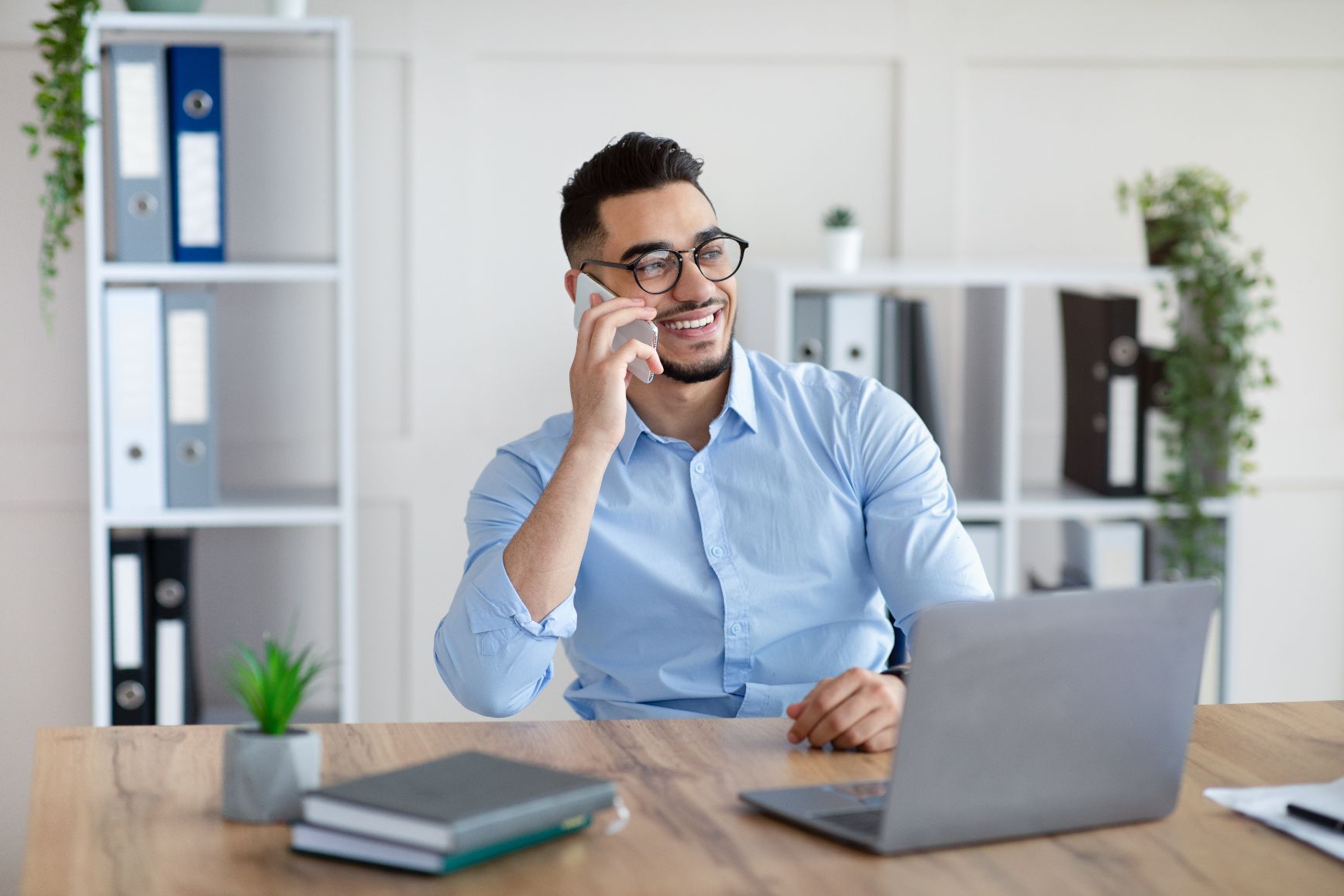 Business man talking on the phone while working on a laptop at a desk