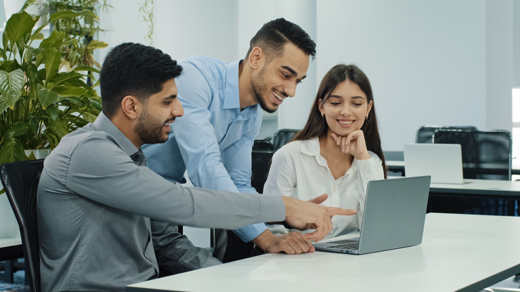 Co-workers huddled around computer working 