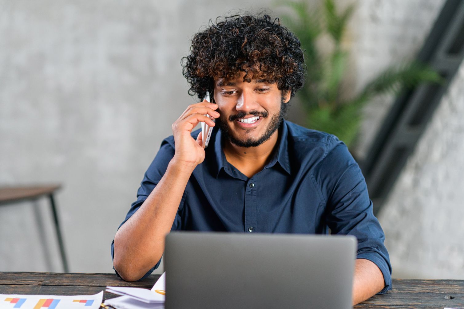 Business man working on computer at a desk while talking on the phone