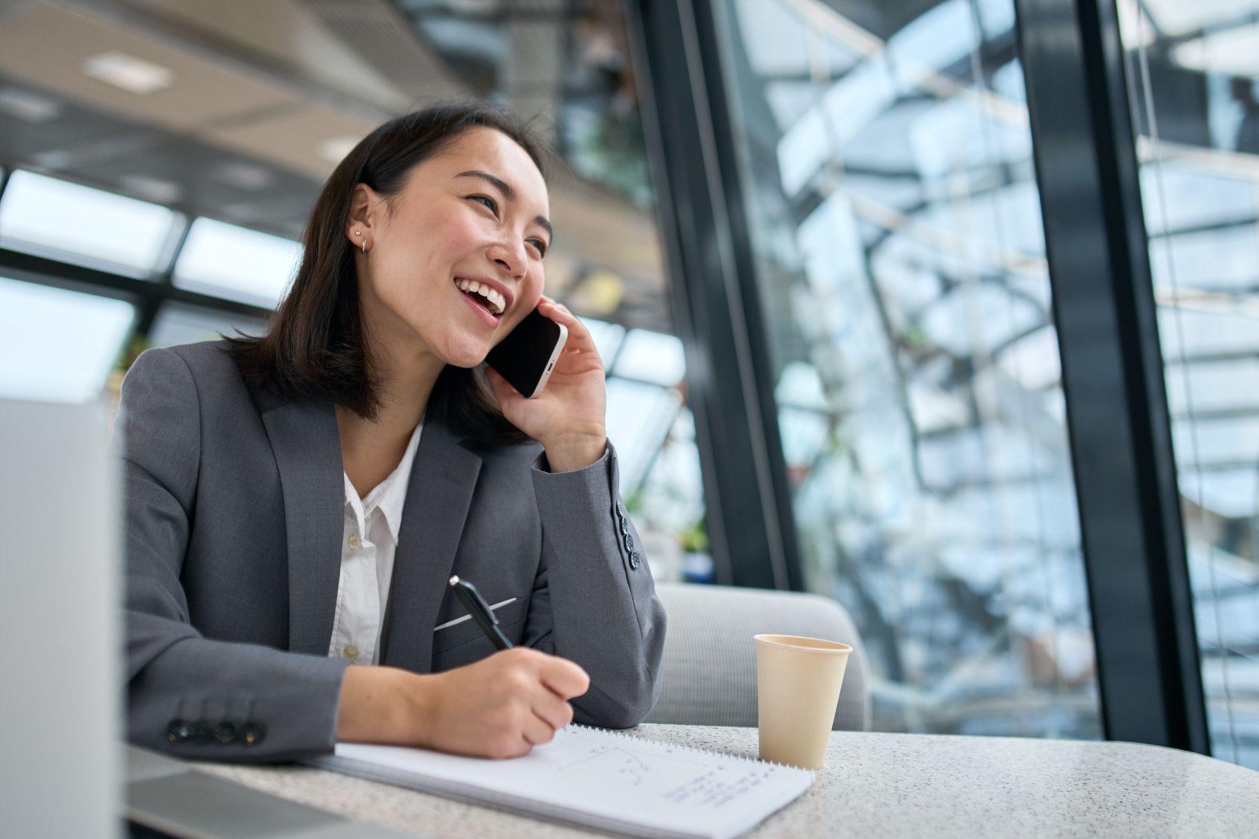 Business woman talking on phone while taking notes