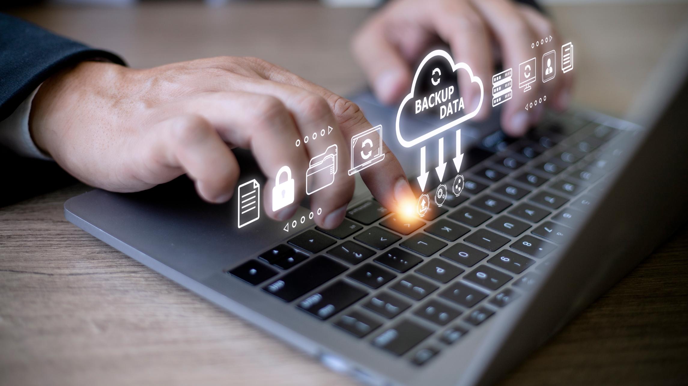 Person's hands typing on keyboard with icons for backing up data