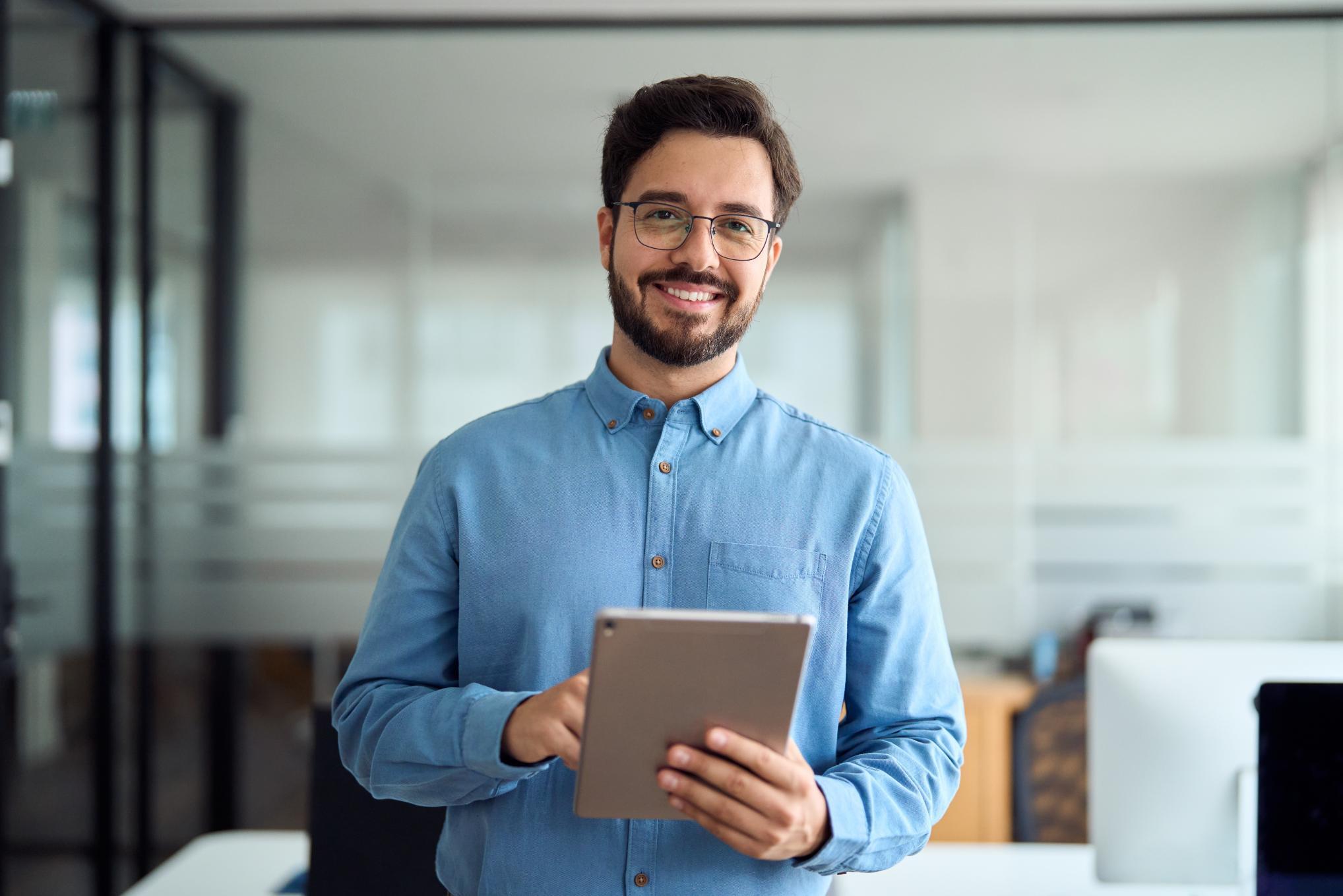 Business man holding tablet in an office smiling at camera
