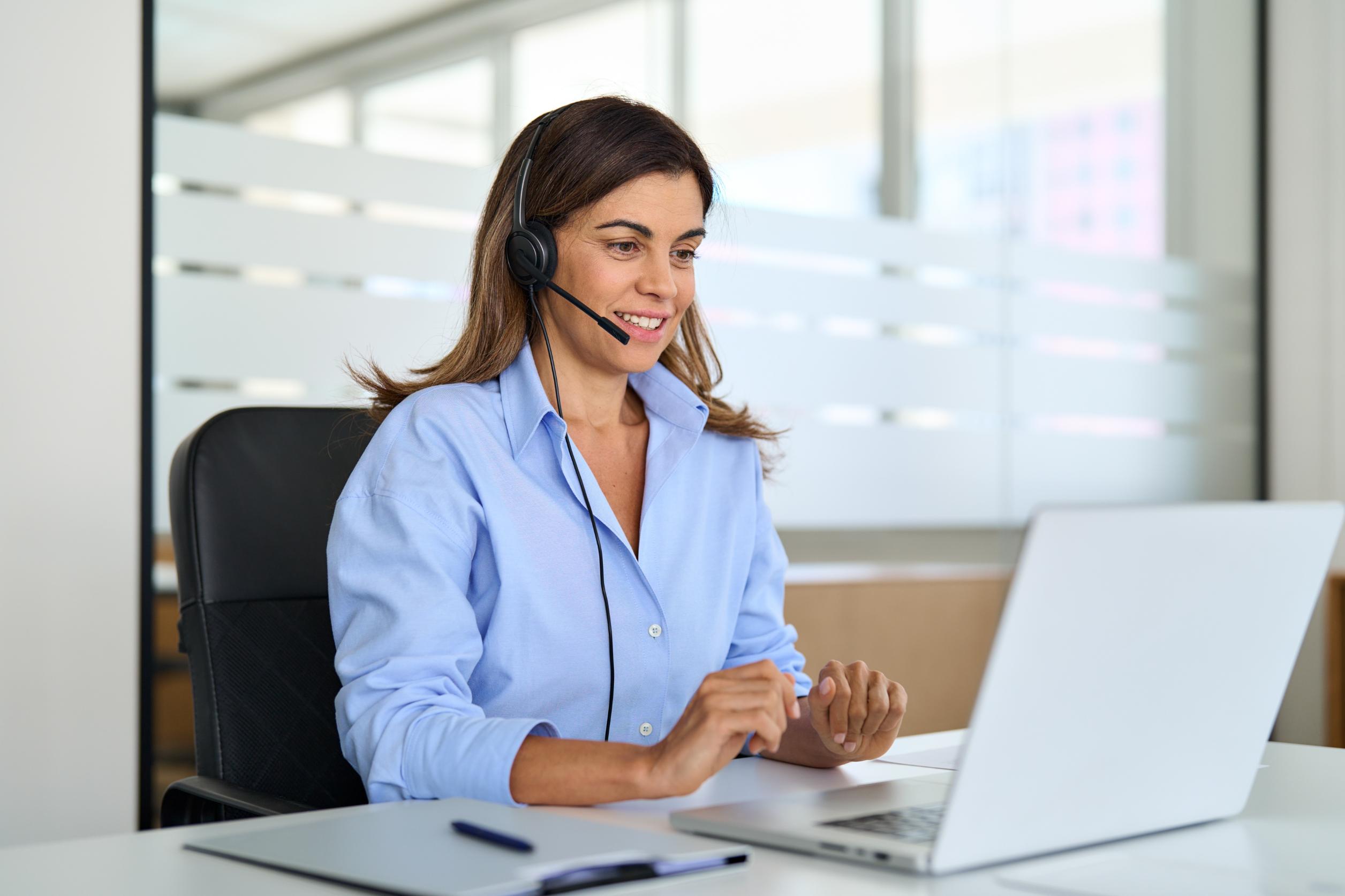 Business woman working on computer at a desk with headset on