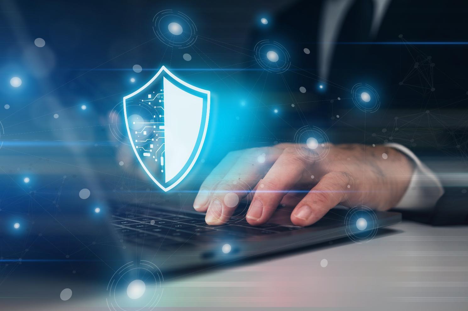 Person typing on laptop with security graphic over the image
