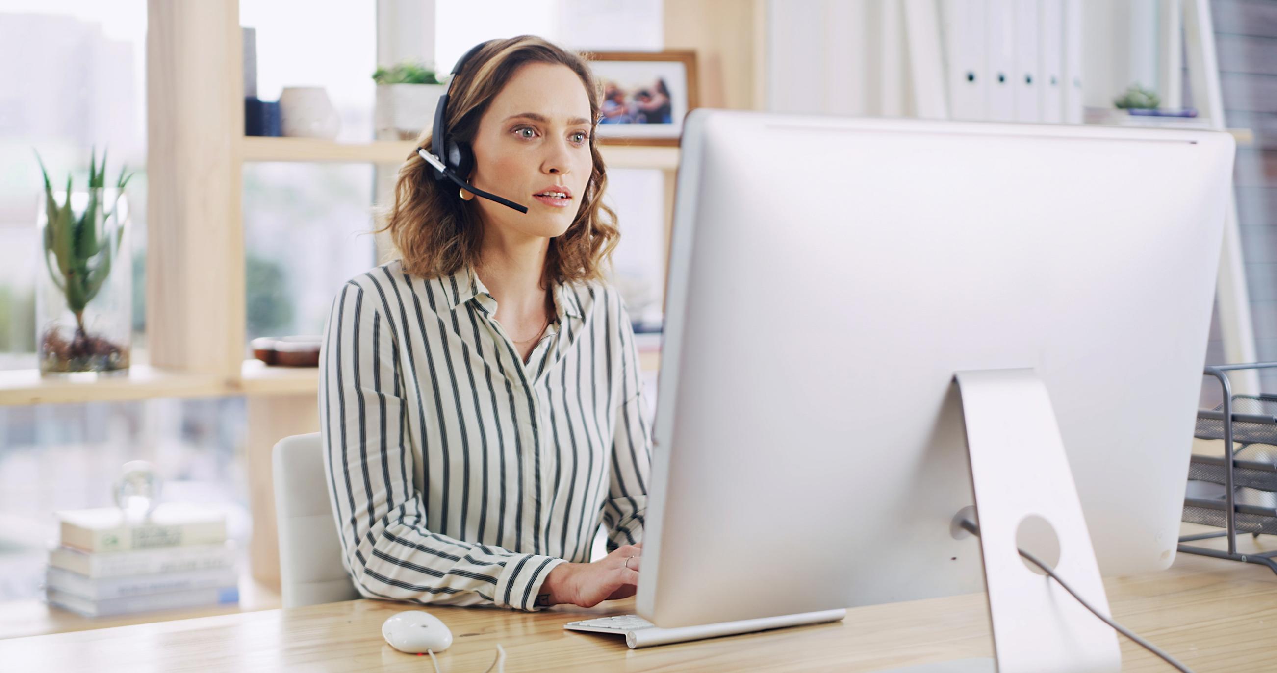 Person typing on a laptop with a headset on