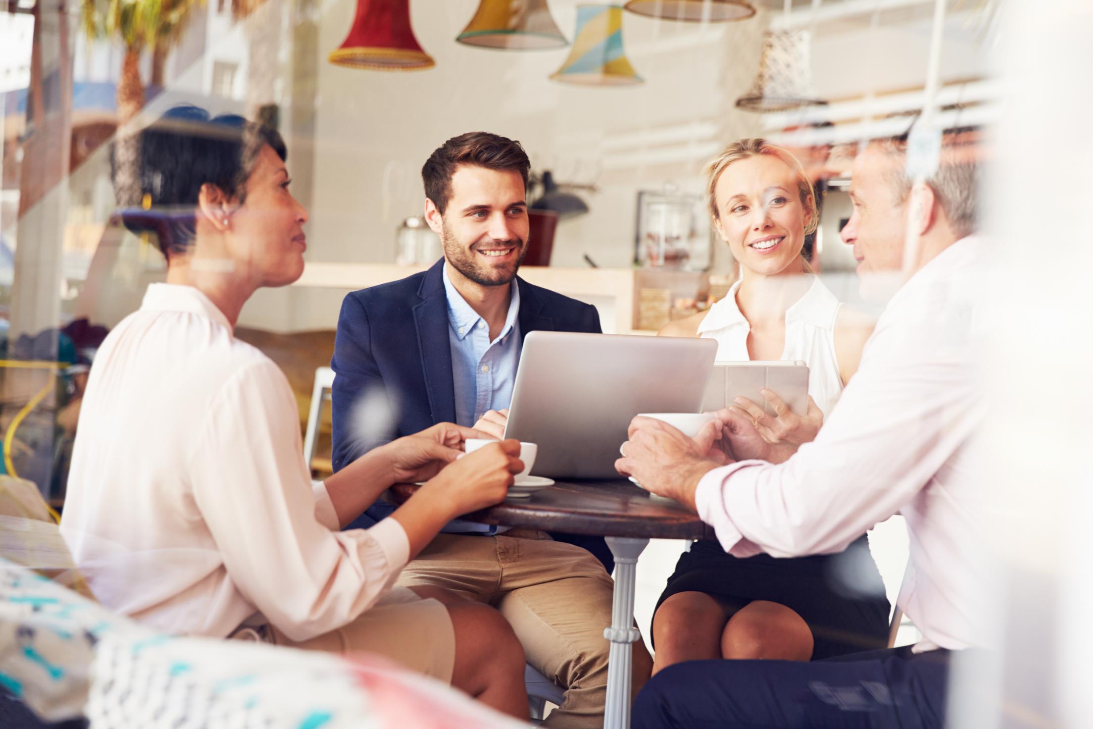 Group of business professionals working on laptops together at a table