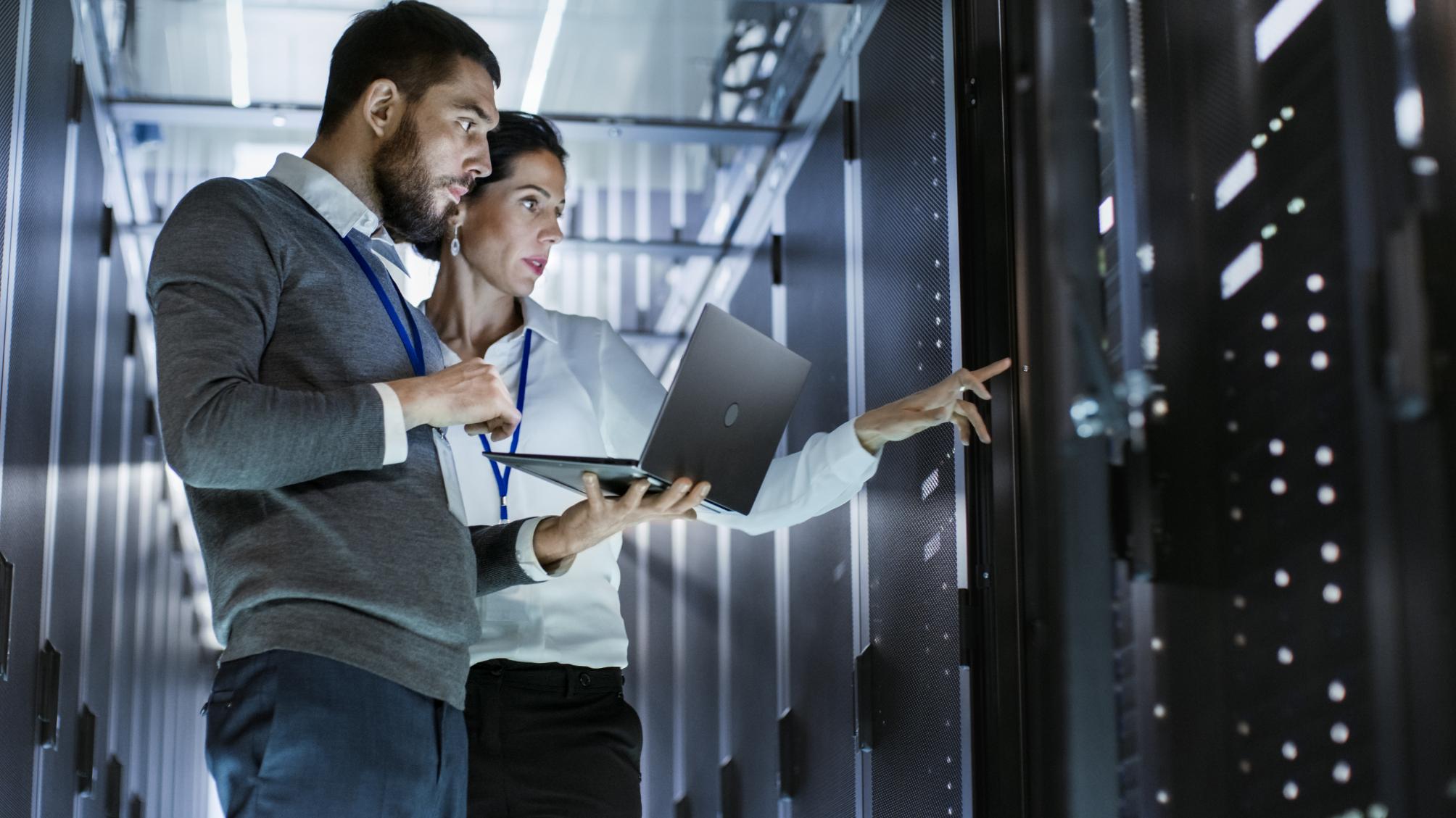 Two business people working on a laptop in a data center