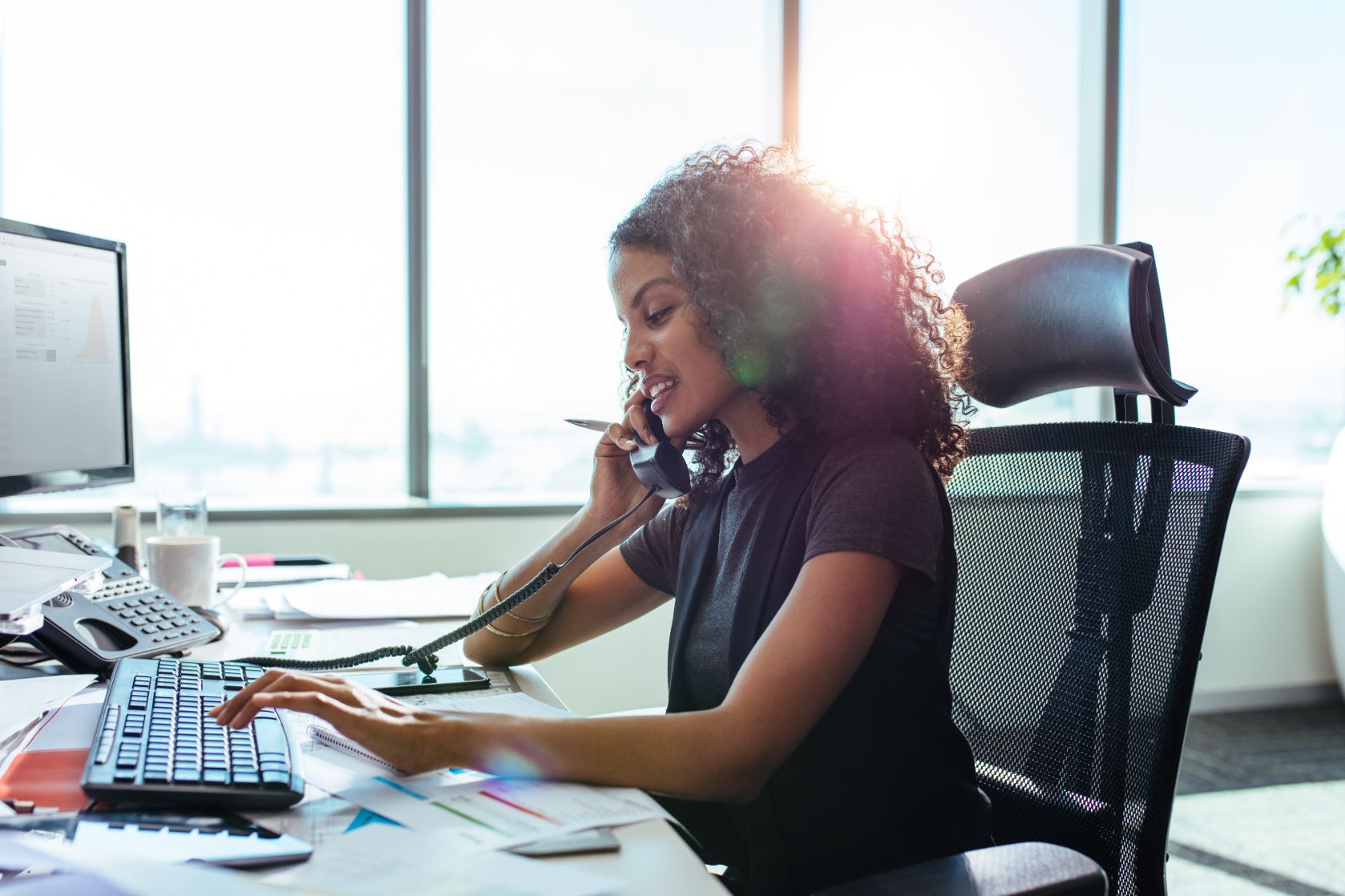 Business woman talking on phone and working on computer