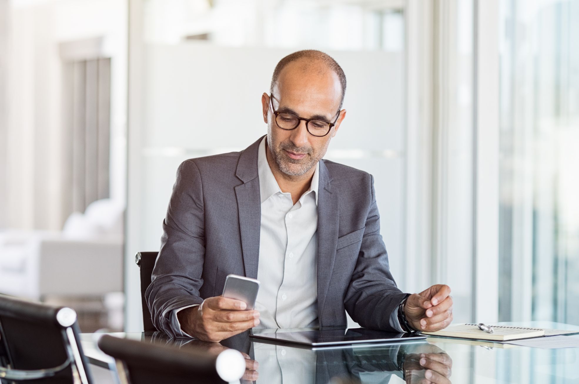 Business man looking at cellphone at a desk